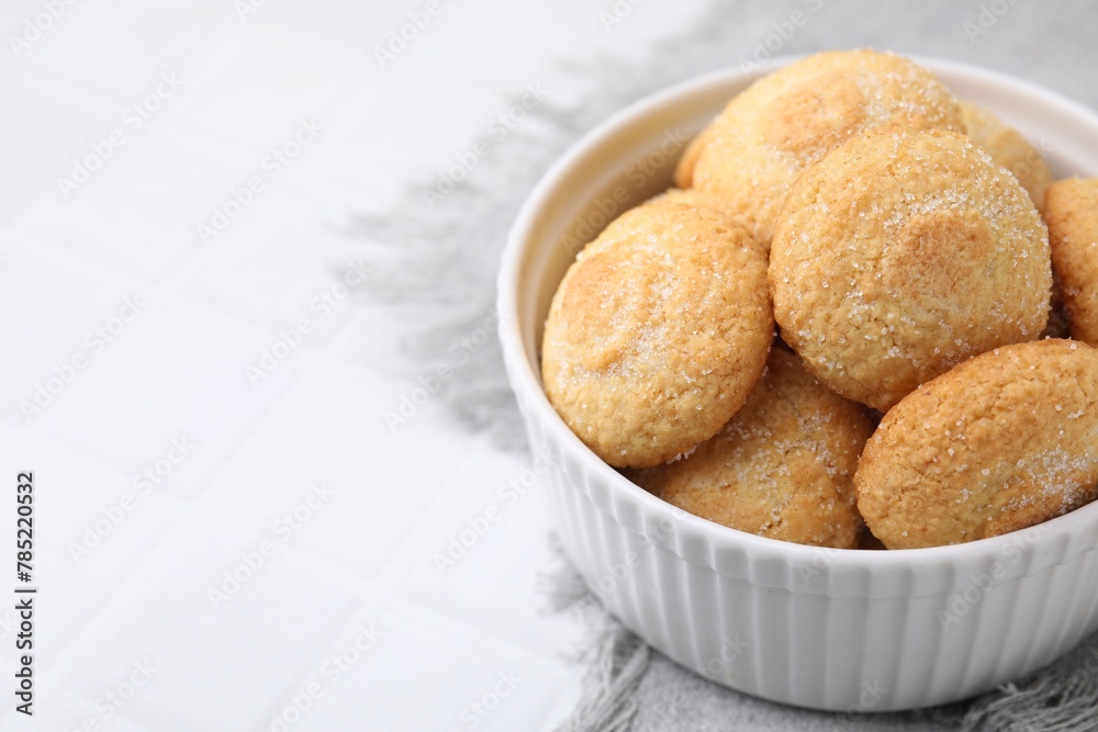 Tasty sugar cookies in bowl on white tiled table, closeup. Space for text