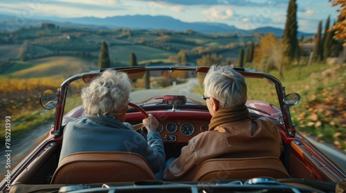 Old senior couple is driving a blue convertible car. People ride in fashionable retro cabriolet. A fun road trip. Beautiful vintage car. Summer auto travel. Happy holidays. Weekend adventure.
