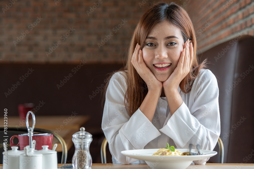 Woman in white clothes holding and smell white dish plate with pasta homemade spaghetti marinara in restaurant background. Lady smell and eat pasta spaghetti by fork. Woman in white clothes holding and smell white dish plate with pasta homemade spaghetti marinara in restaurant background. Lady smell and eat pasta spaghetti by fork.