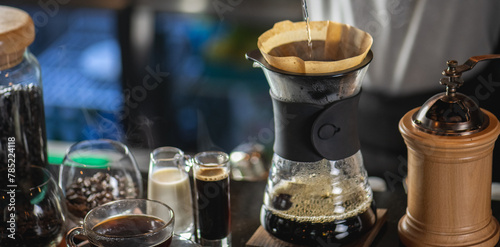 drip coffee, Barista making drip coffee by pouring spills hot water on coffee ground with prepare filter from copper pot to glass transparent chrome drip maker on wooden table in cafe shop