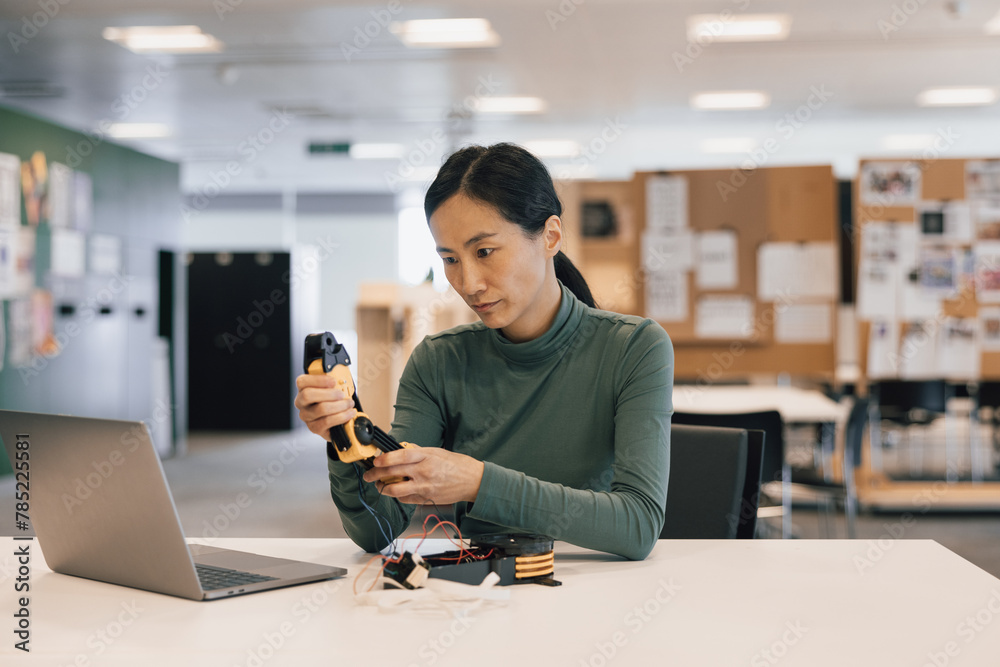 Woman working on mechanics of a robotic arm Woman working on mechanics of a robotic arm