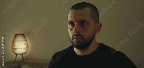 Indoor portrait of serious bearded man with looking astonished away sitting in his room. Peope and reaction concept photo