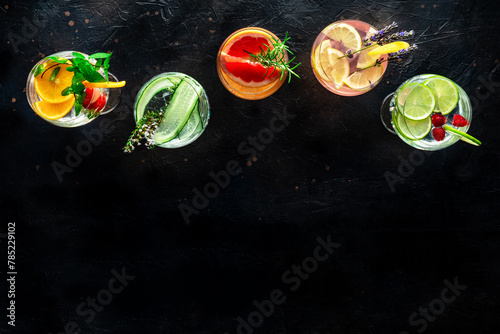 Fancy cocktails with fresh fruit. Gin and tonic drinks with ice at a party, on a black background, shot from above with a place for text