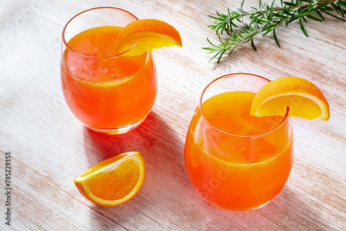 Orange drinks with rosemary on a wooden background, fresh pressed juice with fruit slices on a rustic table