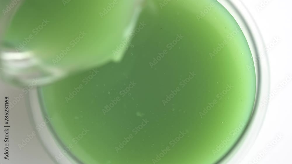 Pouring of the green smoothie into a glass. Healthy eating concept.