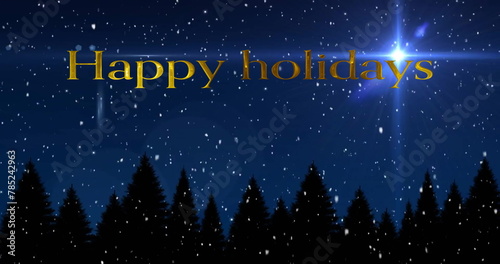 Image of happy holidays text and snow falling over trees on blue background
