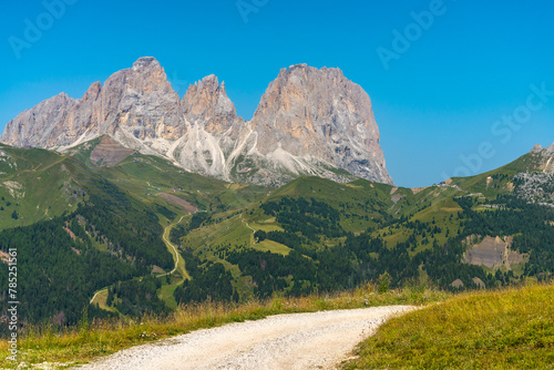 The famous massif named "Sassolungo", in Dolomites mountain chain, Italy. Dirt road for hikers on the foreground. Blue sky on the background.