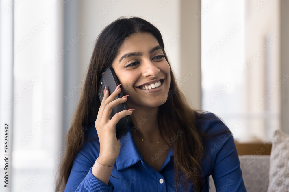Cheerful young adult Indian girl speaking on mobile phone, chatting with friend, enjoying communication, smartphone connection. Happy customer, client making order on telephone Cheerful young adult Indian girl speaking on mobile phone, chatting with friend, enjoying communication, smartphone connection. Happy customer, client making order on telephone