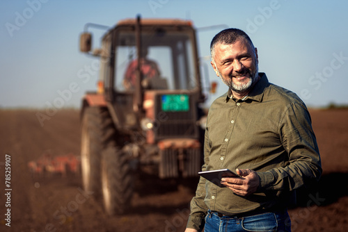 Portrait of satisfied mature farmer standing in field with tablet supervises the cultivation of soil. © Zoran Zeremski