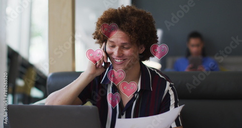 Image of hearts over caucasian businessman talking on smartphone