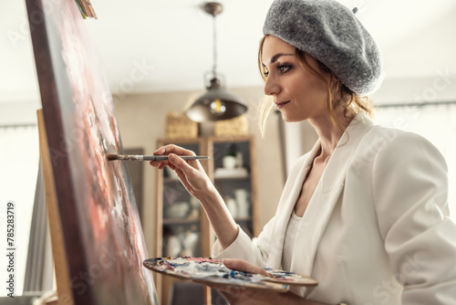 Beautiful female painter enjoying while painting in home art studio. Woman Artist Works on Abstract acrylic painting in the art studio