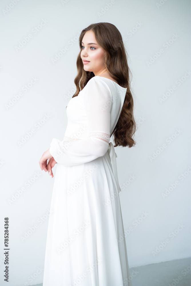 portrait of beautiful young woman in white wedding dress posing in studio.