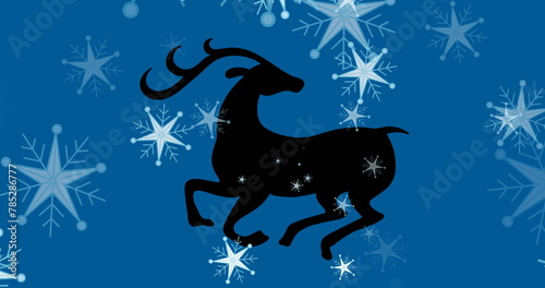 Image of reindeer over snow falling on blue background