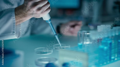 Close Up of a Scientist Pouring Clear Liquid into Glass Dishes with a Micro Pipette, Conducting Scientific Experiment in Laboratory Setting. Chemistry Concept for Medical Research and Analysis photo