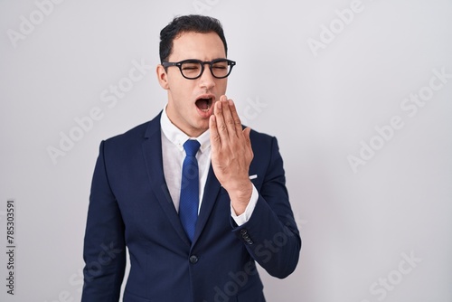 Young hispanic man wearing suit and tie bored yawning tired covering mouth with hand. restless and sleepiness. © Krakenimages.com