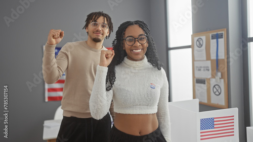 A cheerful man and woman with 'i voted' stickers, raising their fists in unity at an american polling station, symbolizing democratic participation. photo