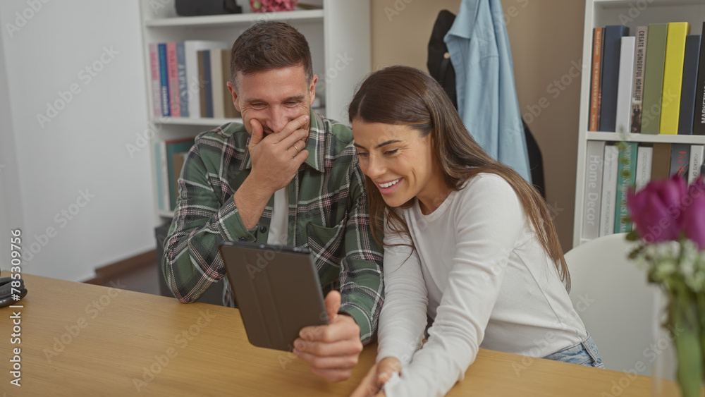 A smiling woman and a laughing man engaging with a tablet in a cozy living room setting A smiling woman and a laughing man engaging with a tablet in a cozy living room setting