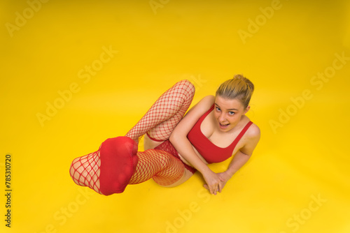 Woman in red fishnet stockings posed on yellow background