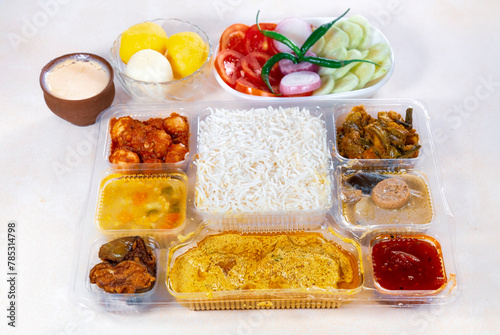 Indian Bengali mixed thali with veggie and non-vegetarian dishes, comprising plain rice, vegetable dishes, spicy fish curry, salad, and dessert.