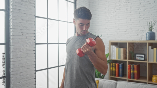 Handsome hispanic man lifting dumbbell in modern living room interior photo