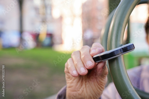 Elder hand holding a plastic piece of a outdoor gym