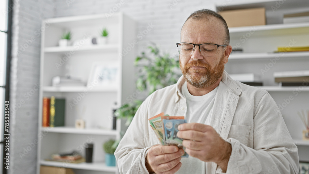 Handsome, bearded caucasian man, working in a business office, seriously thinking about the uncertain future while counting australian dollars, doubting his investment strategy. Handsome, bearded caucasian man, working in a business office, seriously thinking about the uncertain future while counting australian dollars, doubting his investment strategy.