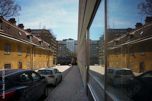 a narrow city street with cars parked on the side of a building