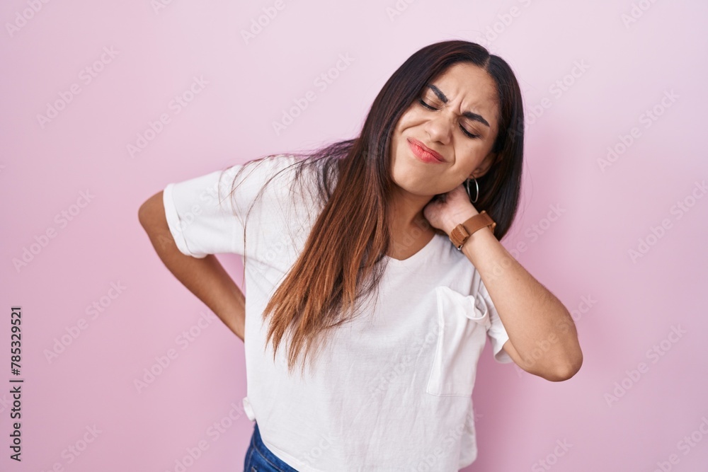 Young arab woman standing over pink background suffering of neck ache injury, touching neck with hand, muscular pain Young arab woman standing over pink background suffering of neck ache injury, touching neck with hand, muscular pain