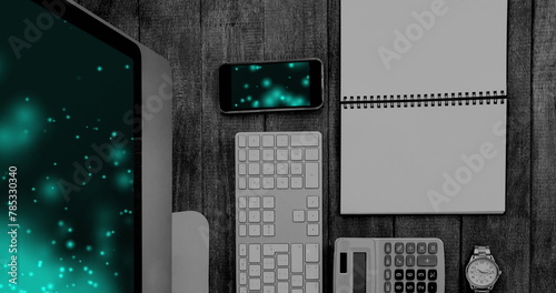 Image of technological devices with light spots on screen on desk
