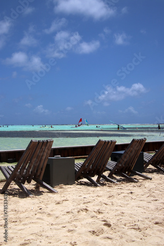 Deckchairs at white sandy Caribbean beach with windsurfers in the distance, Sorobon, Bonaire, Caribbean Netherlands