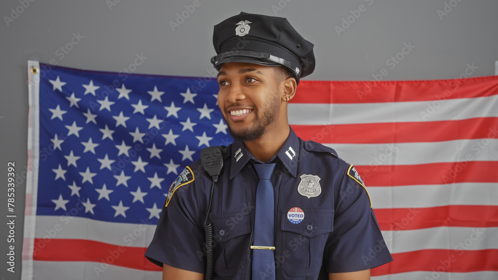 Handsome african american police officer smiles proudly in front of a usa flag. Handsome african american police officer smiles proudly in front of a usa flag.