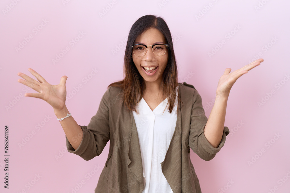 Middle age chinese woman wearing glasses over pink background celebrating crazy and amazed for success with arms raised and open eyes screaming excited. winner concept Middle age chinese woman wearing glasses over pink background celebrating crazy and amazed for success with arms raised and open eyes screaming excited. winner concept