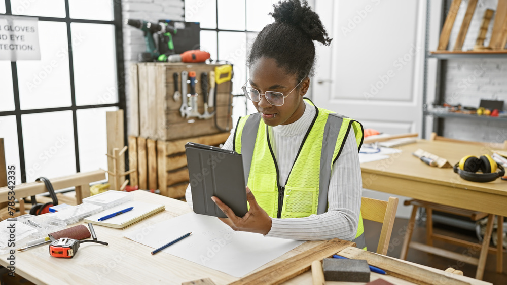 Focused african american woman using tablet in carpentry workshop Focused african american woman using tablet in carpentry workshop