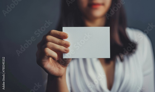 Woman holding blank card close up - Woman in white dress presenting a blank business card, focus on card and hand, concept of introduction or opportunity