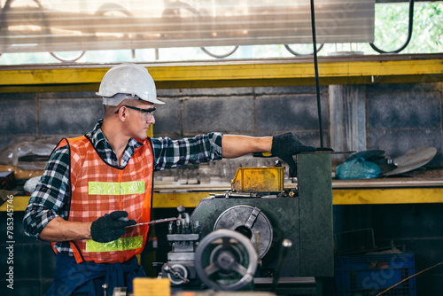 Male engineer metalworker industrial experienced operator technician worker in safety hard helmet working on lathe machine, professional man in industry technology manufacturing factory workshop