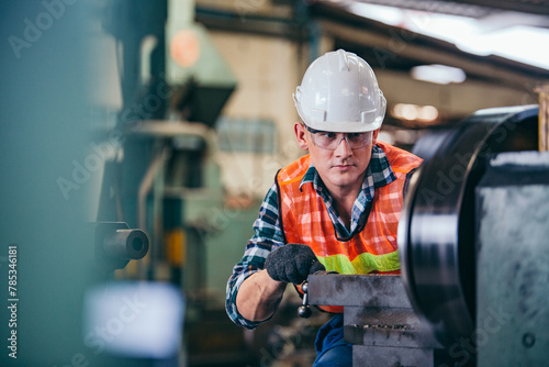 Male engineer metalworker industrial experienced operator technician worker in safety hard helmet working on lathe machine, professional man in industry technology manufacturing factory workshop