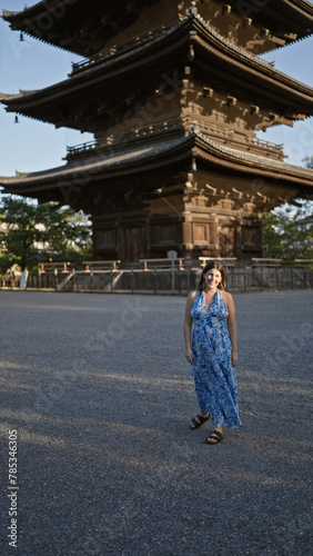 Beautiful hispanic woman standing, smiling confidently in front of japan's to-ji temple, radiating happiness and carefree joy, her friendly expressiveness making this kyoto park even more enjoyable.