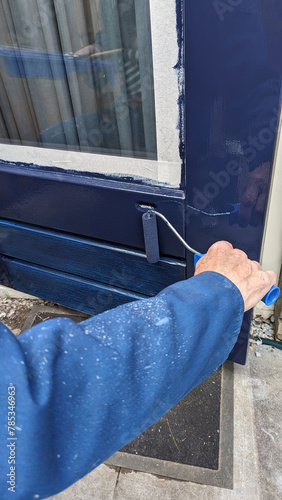 painting a door with blue paint with a roller