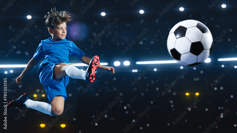 Aesthetic Shot Of Athletic Child Soccer Football Player Jumping And Kicking Ball Mid Air On Black Background Under Spotlight. Young Boy Scoring Beautiful Winning Goal During Championship Final Match