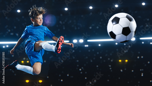 Aesthetic Shot Of Athletic Child Soccer Football Player Jumping And Kicking Ball Mid Air On Black Background Under Spotlight. Young Boy Scoring Beautiful Winning Goal During Championship Final Match © Gorodenkoff