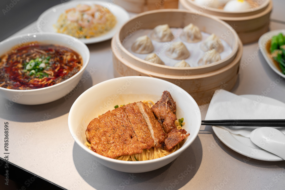 Table meal in Chinese style. Focus on delicious noodle top with fried pork. Table meal in Chinese style. Focus on delicious noodle top with fried pork.