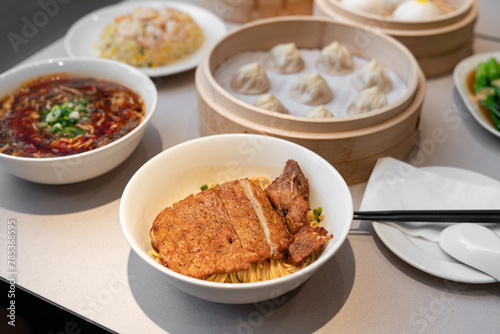 Table meal in Chinese style. Focus on delicious noodle top with fried pork.