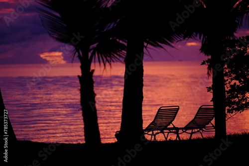 A view of two long chairs in silhouette on a small beach of the Rangiroa Atoll. Tuamotu Archipelago, French Polynesia, November 11, 2022