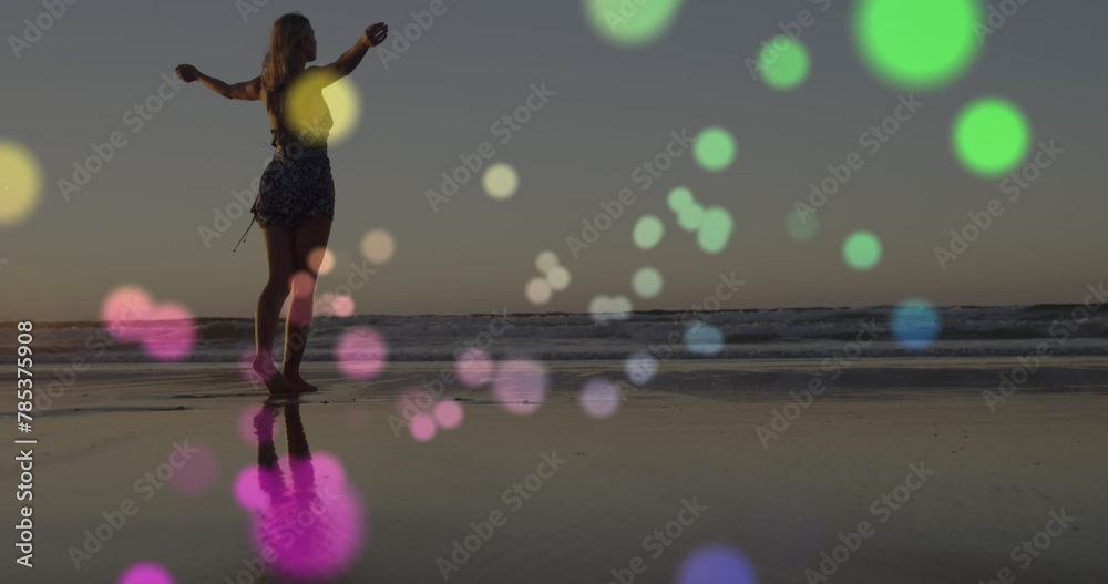 Fototapeta premium Image of lights over happy caucasian woman walking on beach