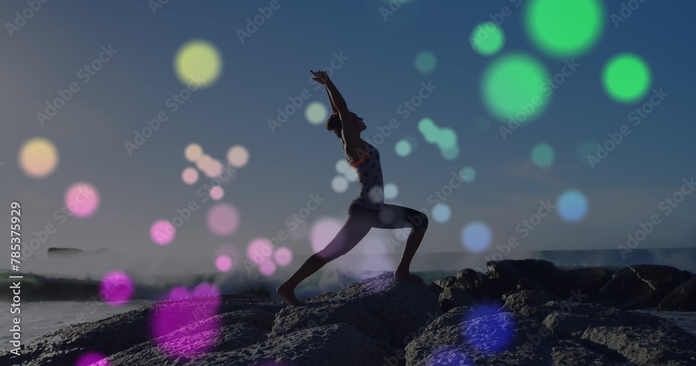 Image of lights over caucasian woman practicing yoga on beach Image of lights over caucasian woman practicing yoga on beach