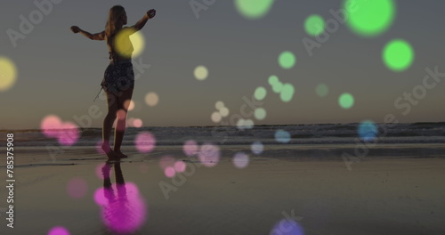 Image of lights over happy caucasian woman walking on beach