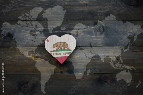 wooden heart with national flag of california state near world map on the wooden background.
