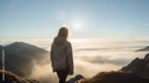 Back view of woman female standing on the cliff, watching sunrise breathtaking and enjoy it. photo