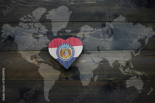 wooden heart with national flag of missouri state near world map on the wooden background.