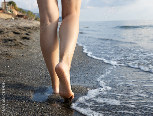feet of a girl walking on the sand by the sea. selective focus . High quality photo